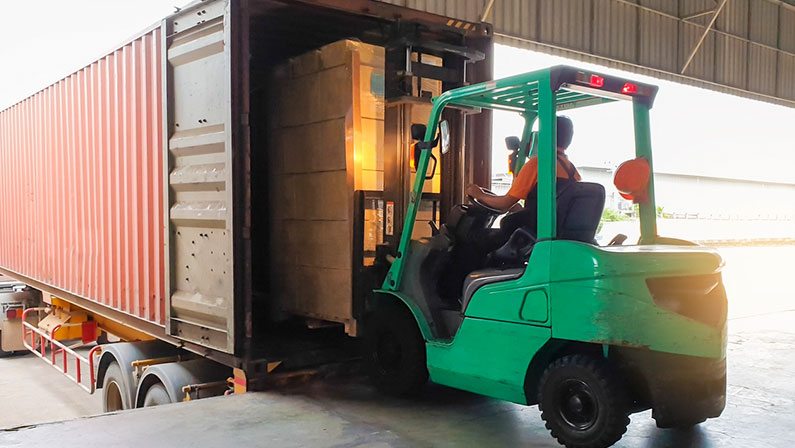 Forklift driver loads a pallet into a truck container